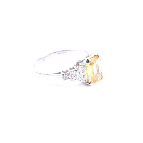 634 - A platinum, diamond, and yellow sapphire ring set with a mixed emerald-cut yellow sapphire of approx... 