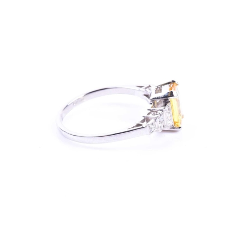 634 - A platinum, diamond, and yellow sapphire ring set with a mixed emerald-cut yellow sapphire of approx... 