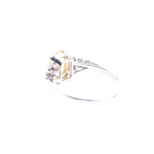 634 - A platinum, diamond, and yellow sapphire ring set with a mixed emerald-cut yellow sapphire of approx... 