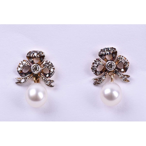 646 - A pair of diamond and pearl drop earrings, the silver set gold-backed bow-shaped mounts inset with r... 