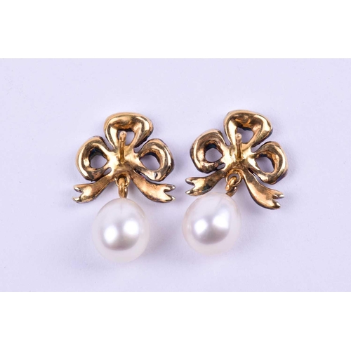 646 - A pair of diamond and pearl drop earrings, the silver set gold-backed bow-shaped mounts inset with r... 