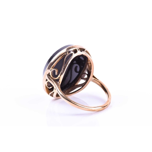 653 - A yellow metal and micro mosaic ring, the black onyx mount inlaid with a floral design, shank unmark... 