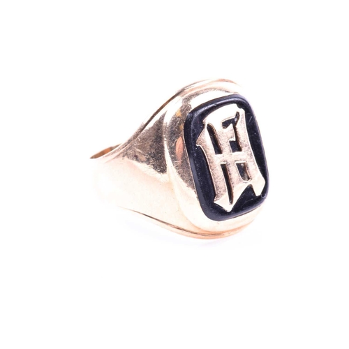 684 - A yellow metal gents ring, bearing black onyx plaque with initials FH monogrammed to centre, shank u... 