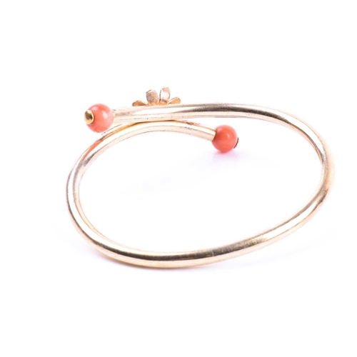 702 - A late 19th / early 20th century yellow metal and coral bracelet, of crossover design, centred with ... 