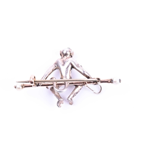 706 - An unusual paste gemstone monkey brooch, the monkey seated on a yellow metal bar brooch with pearl t... 