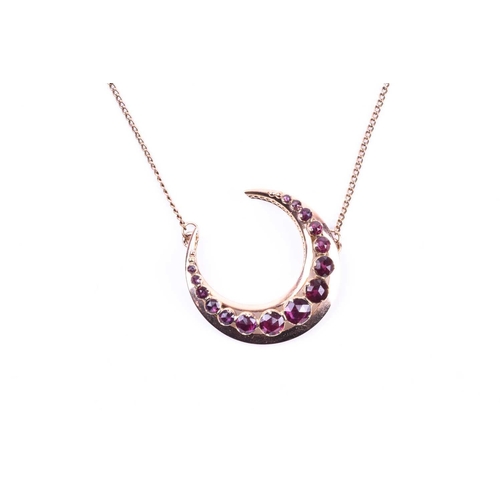 712 - A 9ct yellow gold and garnet crescent brooch, set with graduated rose-cut garnets, suspended on a 9c... 