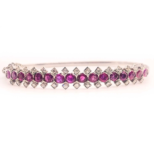 733 - A fine diamond and ruby bangle bracelet, set with a row of mixed-cut rubies of approximately 3.70 ca... 