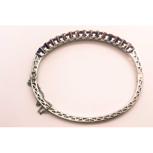 733 - A fine diamond and ruby bangle bracelet, set with a row of mixed-cut rubies of approximately 3.70 ca... 