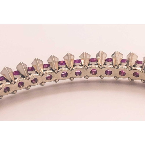 733 - A fine diamond and ruby bangle bracelet, set with a row of mixed-cut rubies of approximately 3.70 ca... 