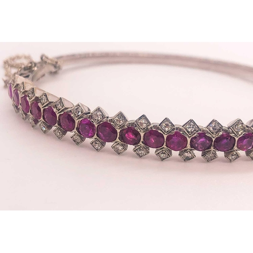 733 - A fine diamond and ruby bangle bracelet, set with a row of mixed-cut rubies of approximately 3.70 ca... 