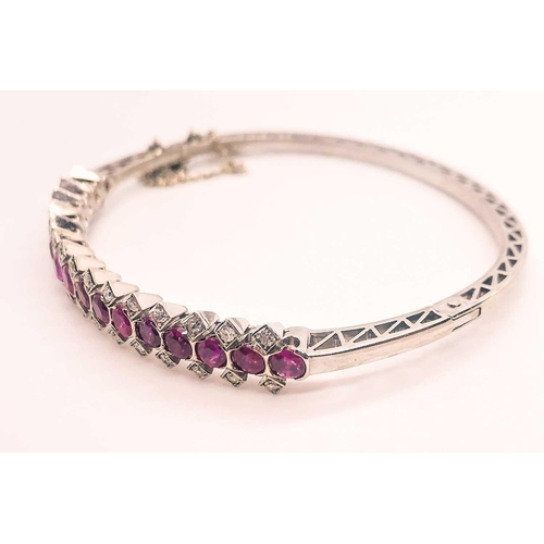 733 - A fine diamond and ruby bangle bracelet, set with a row of mixed-cut rubies of approximately 3.70 ca... 