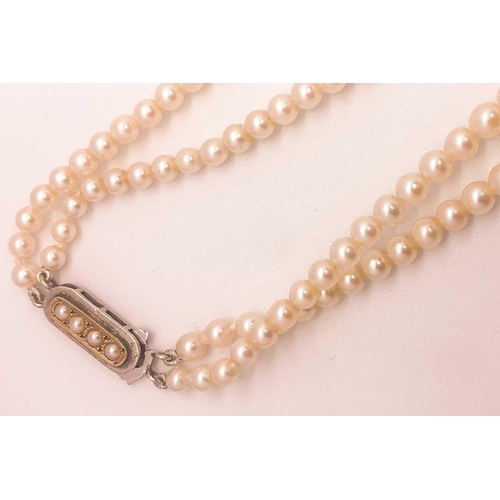 734 - A double strand cultured pearl necklace, the pearls ranging from approximately 3 - 7 mm, fastened wi... 