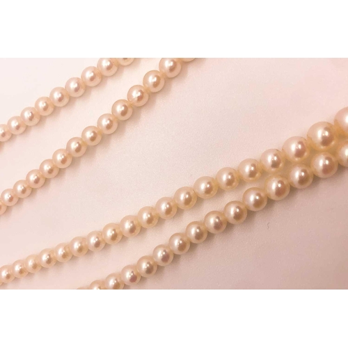 734 - A double strand cultured pearl necklace, the pearls ranging from approximately 3 - 7 mm, fastened wi... 