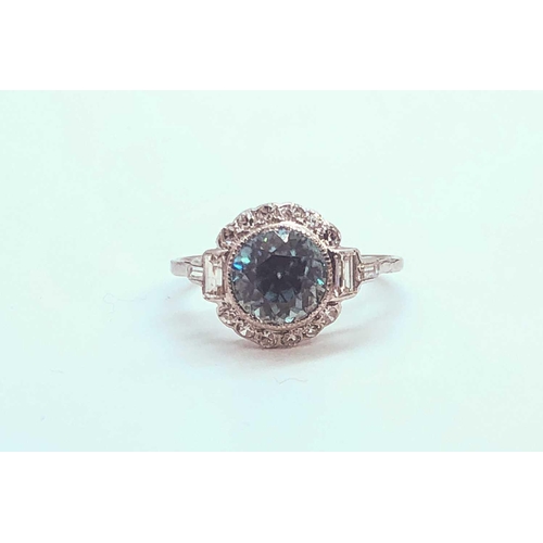 743 - A diamond and blue zircon ring, set with a natural zircon of approximately 2.54 carats, within a bor... 