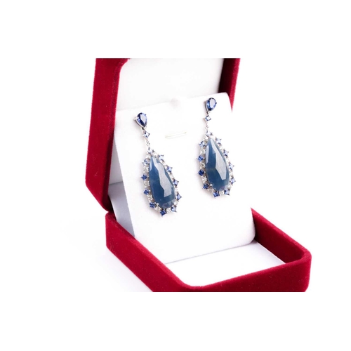 138 - A pair of sapphire pendant earrings, the tear-drop shaped faceted blue grey sapphire matrix centre w... 