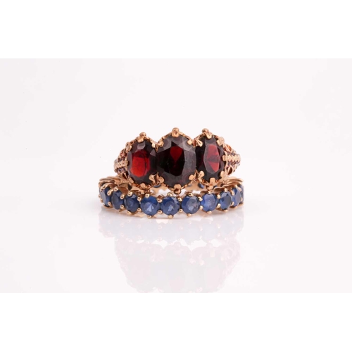 25 - A three stone half hoop garnet ring, the graduated oval garnets in ornate carved 9ct yellow gold mou... 