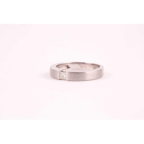 26 - An 18ct white gold and diamond ring, the matte-finished mount inset with a princess-cut diamond of a... 