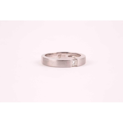 26 - An 18ct white gold and diamond ring, the matte-finished mount inset with a princess-cut diamond of a... 