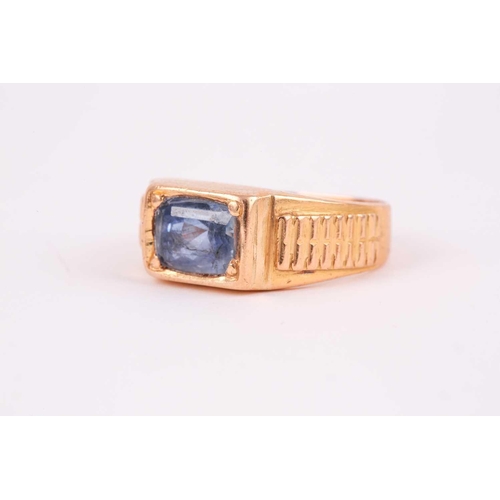 27 - A yellow metal and sapphire ring, set east to west with a mixed rectangular-cut sapphire, the stone ... 