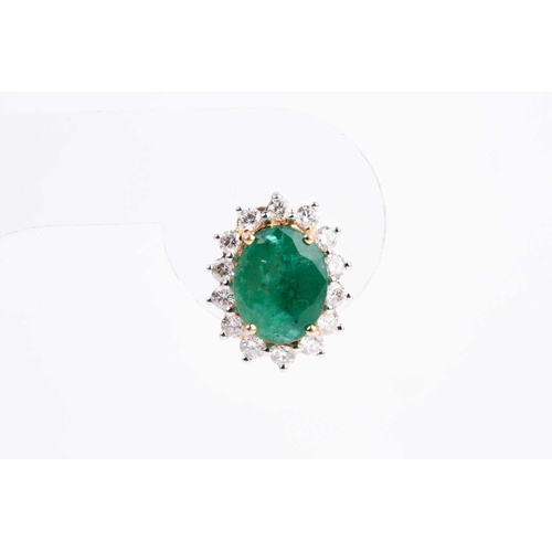 33 - A pair of emerald and diamond cluster earrings, the mixed oval-cut emerald in four claw mount above ... 