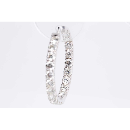 54 - A fine pair of diamond earrings, each set with round brilliant-cut diamonds to the front of the hoop... 