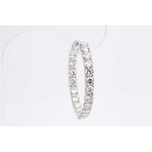 54 - A fine pair of diamond earrings, each set with round brilliant-cut diamonds to the front of the hoop... 