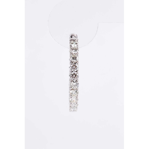 54 - A fine pair of diamond earrings, each set with round brilliant-cut diamonds to the front of the hoop... 