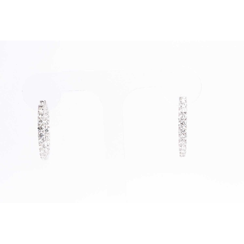 54 - A fine pair of diamond earrings, each set with round brilliant-cut diamonds to the front of the hoop... 