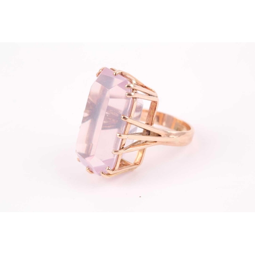 82 - A yellow metal and pink quartz ring, set with a rectangular-cut stone, in a yellow metal basket moun... 