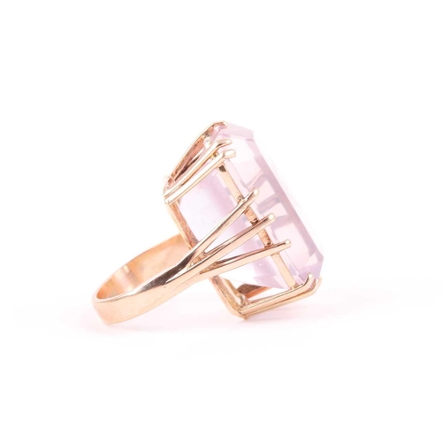 82 - A yellow metal and pink quartz ring, set with a rectangular-cut stone, in a yellow metal basket moun... 