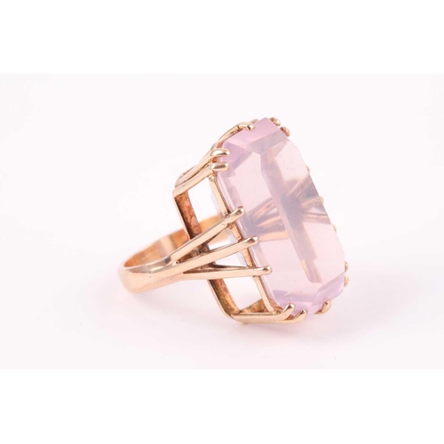 82 - A yellow metal and pink quartz ring, set with a rectangular-cut stone, in a yellow metal basket moun... 