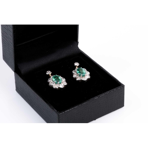 86 - A pair of diamond and emerald cluster drop earrings, each set with a mixed oval-cut emerald within a... 