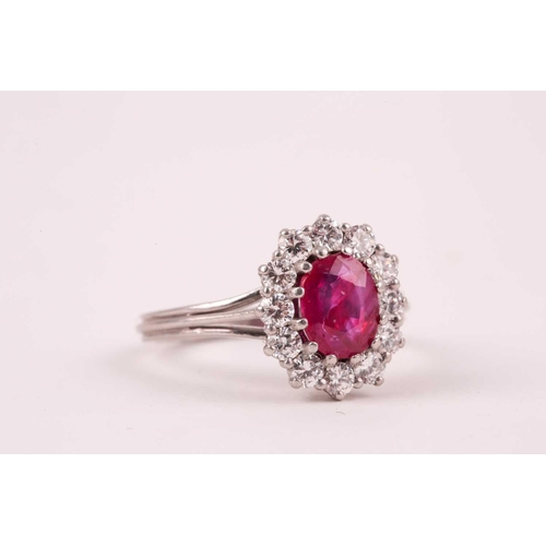 9 - A ruby and diamond cluster ring, the oval mixed-cut ruby, approximately 1ct, surrounded by twelve br... 