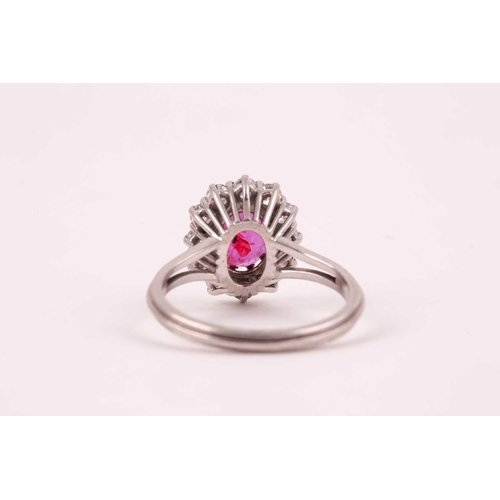 9 - A ruby and diamond cluster ring, the oval mixed-cut ruby, approximately 1ct, surrounded by twelve br... 