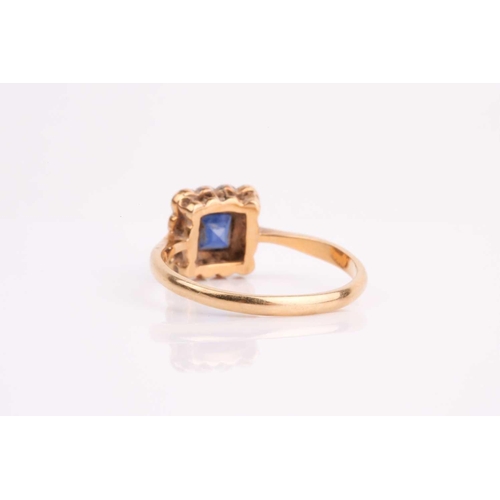 90 - An early 20th century sapphire and diamond cluster ring, the calibre cut sapphire in millegrain moun... 