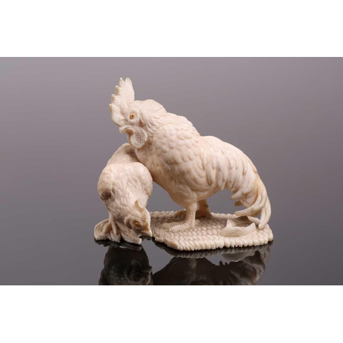 85 - A Japanese ivory okimono, Meiji period, carved as a cockerel and hen, each with horn inset eyes, on ... 