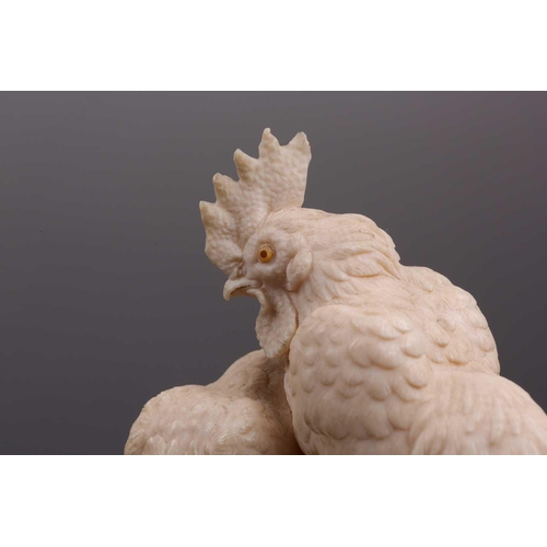 85 - A Japanese ivory okimono, Meiji period, carved as a cockerel and hen, each with horn inset eyes, on ... 