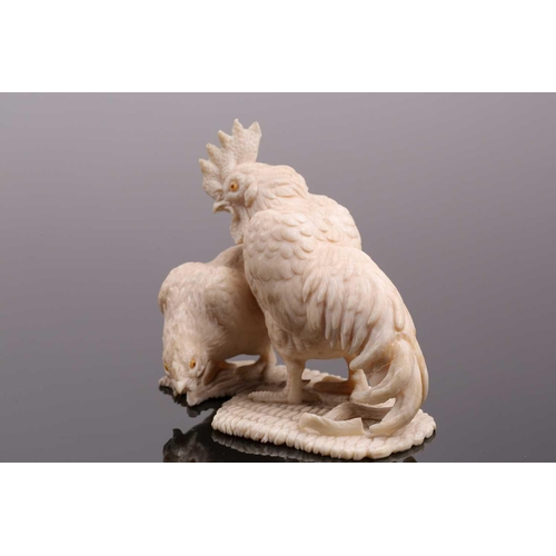 85 - A Japanese ivory okimono, Meiji period, carved as a cockerel and hen, each with horn inset eyes, on ... 