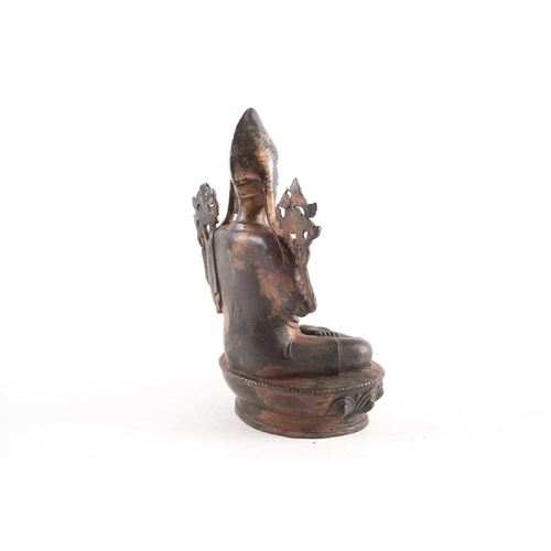 87A - A Tibetan patinated and gilt bronze figure of a Gelpuga Lama seated with flowers about his arms and ... 