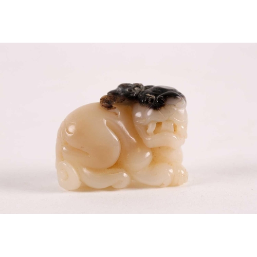 127 - A Chinese, carved off-white and grey jade, Tang-style crouching lion. 81 grams 5 cm long x 3.8 cm hi... 