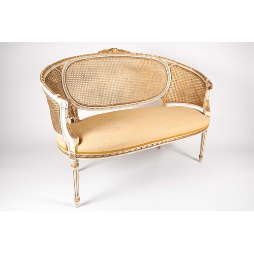 214 - A Louis XVI style ivory painted and parcel-gilt canape settee, 20th century. With carved parchment t... 