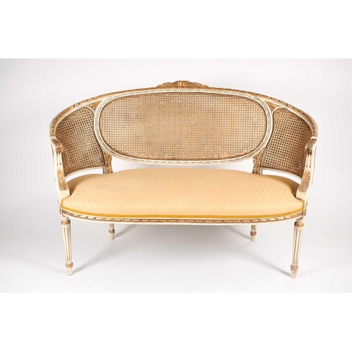 214 - A Louis XVI style ivory painted and parcel-gilt canape settee, 20th century. With carved parchment t... 