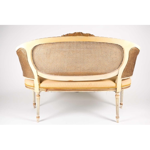 214 - A Louis XVI style ivory painted and parcel-gilt canape settee, 20th century. With carved parchment t... 