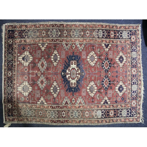 230 - A 20th century Shirvan rug with stepped and barbed lozenges on a raspberry pink ground bearing a wov... 