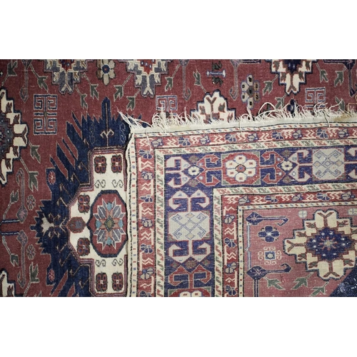 230 - A 20th century Shirvan rug with stepped and barbed lozenges on a raspberry pink ground bearing a wov... 