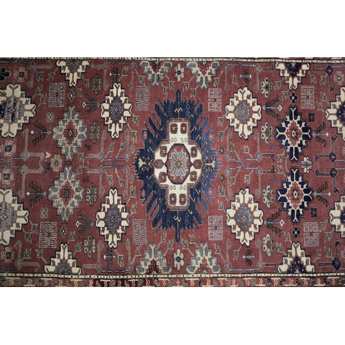 230 - A 20th century Shirvan rug with stepped and barbed lozenges on a raspberry pink ground bearing a wov... 