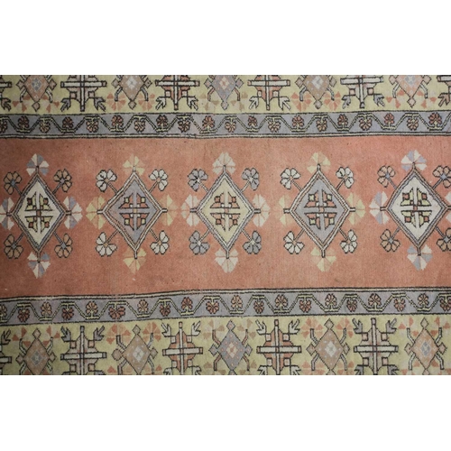 232 - A 20th century Turkish rug with diamond lozenges on a muted red ground within broad borders and frin... 