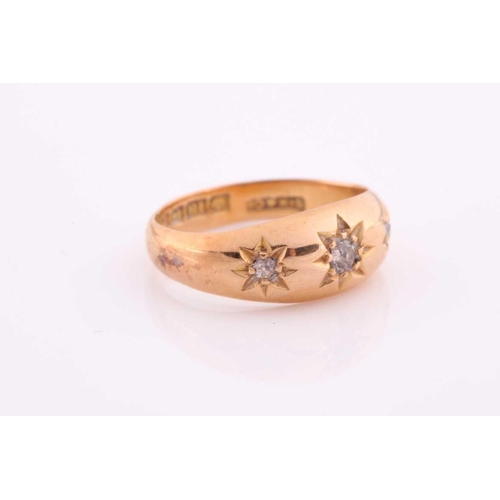 111 - A three stone gypsy set ring, the graduated old brilliant cut diamonds in tapering 18 carat rose gol... 