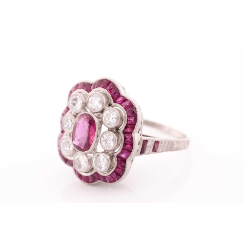 116 - A platinum, diamond, and ruby ring, the stylised mount centred with a mixed oval-cut ruby within a b... 