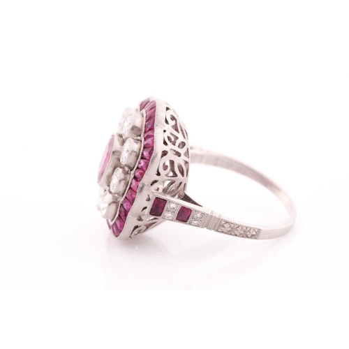 116 - A platinum, diamond, and ruby ring, the stylised mount centred with a mixed oval-cut ruby within a b... 